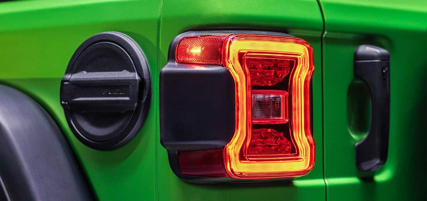 Display The fuel cap, taillamp and cargo area door handle on a lime green 2026 Jeep Wrangler.