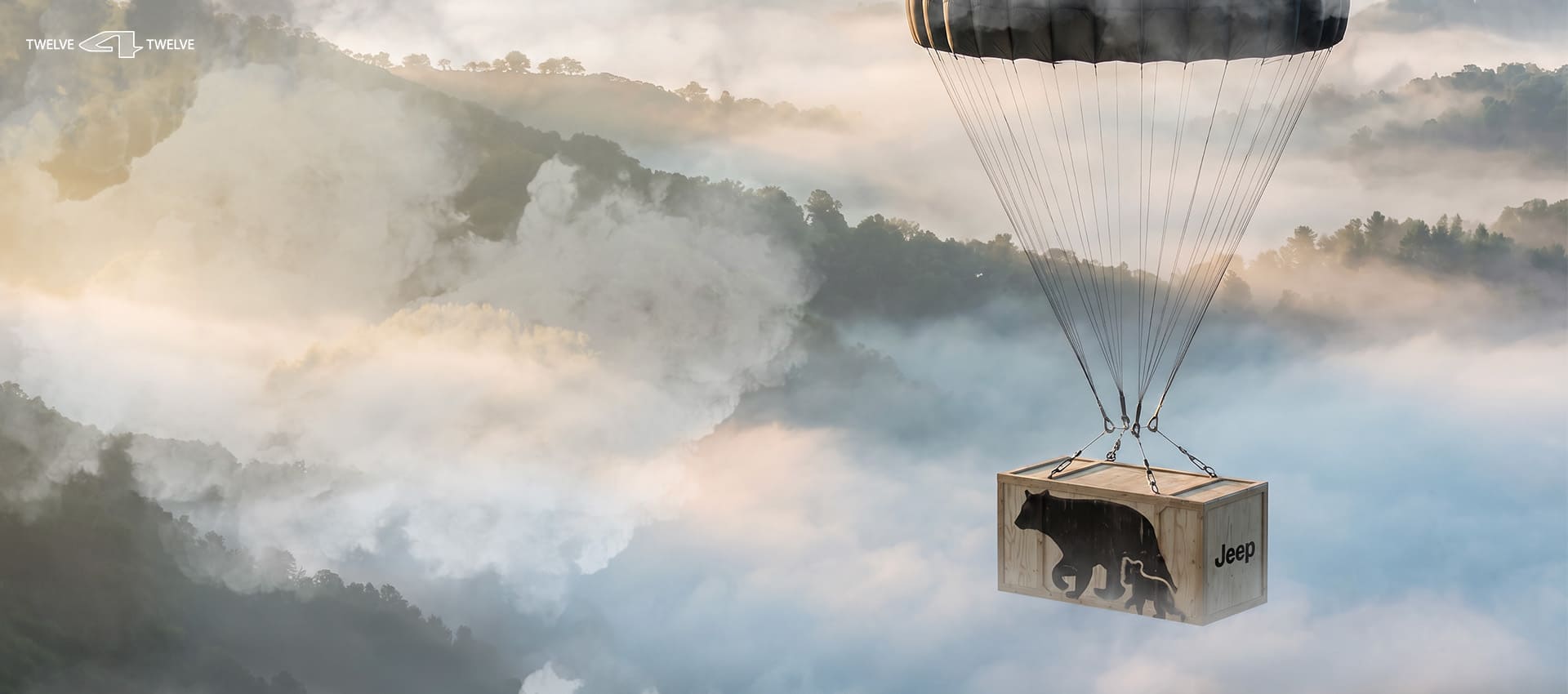 A black parachute carries a crate sailing through a misty daytime sky over mountainous terrain. The crate is labeled Jeep on the side and has silhouette prints of an adult bear and cub printed on the front.