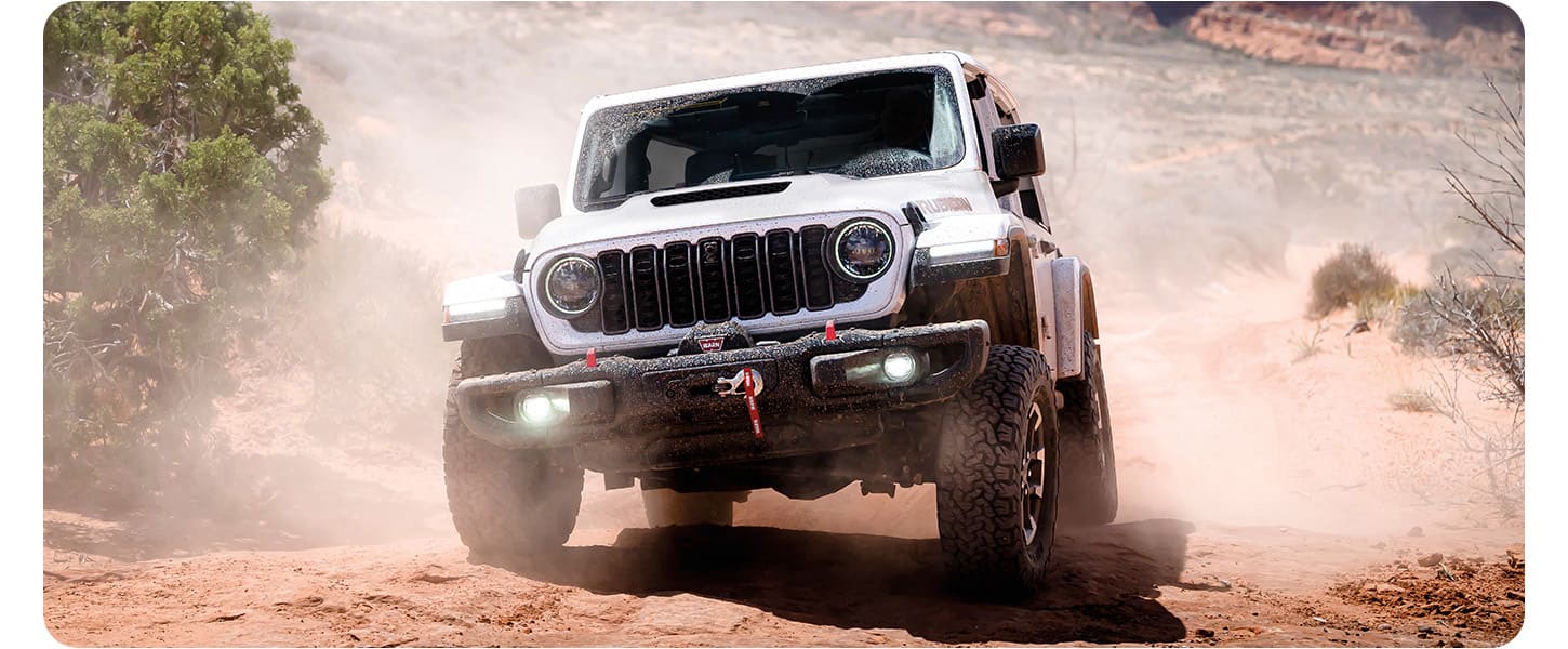 Un Jeep Wrangler Rubicon 2026 blanco de cuatro puertas, circulando por una carretera en la ciudad.
