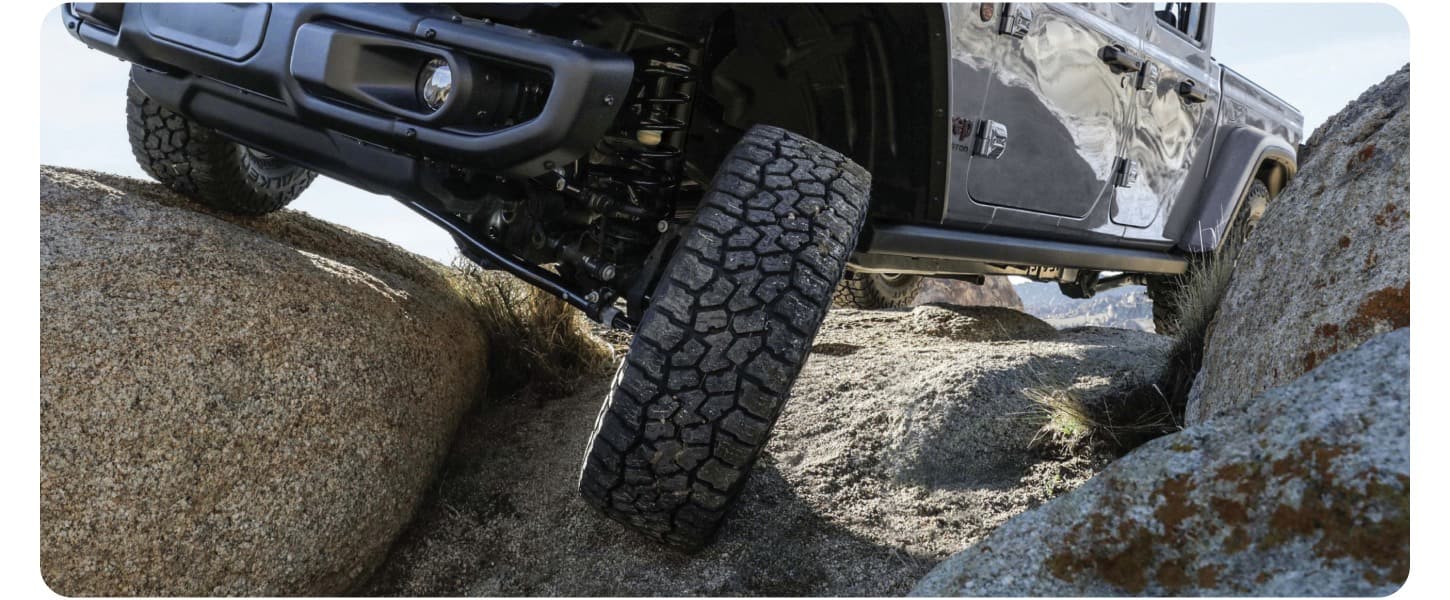 A close-up shot of the tire and suspension of a 2027 Jeep Gladiator as it crawls over rocks.
