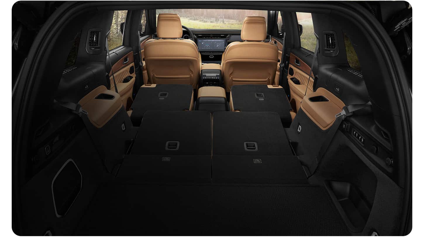 The interior of the 2027 Jeep Grand Cherokee L Summit displaying the cargo area with the second- and third-row seats folded. Shot from the rear.