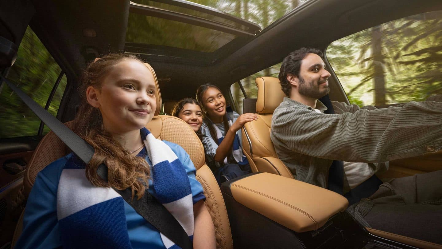 The interior of the 2027 Jeep Grand Cherokee Summit with the male driver and three young female passengers inside--one in the front passenger seat and two in the second row.