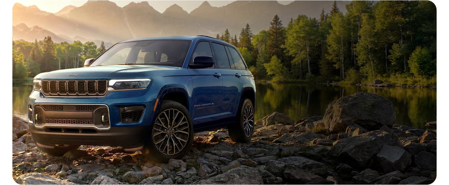 A blue 2027 Jeep Grand Cherokee Overland on a rocky trail off-road.