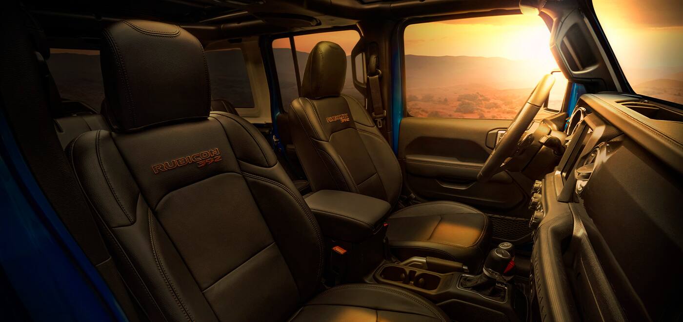 The front seats of the 2021 Jeep Wrangler Rubicon 392, illuminated through the driver-side window by the setting sun.
