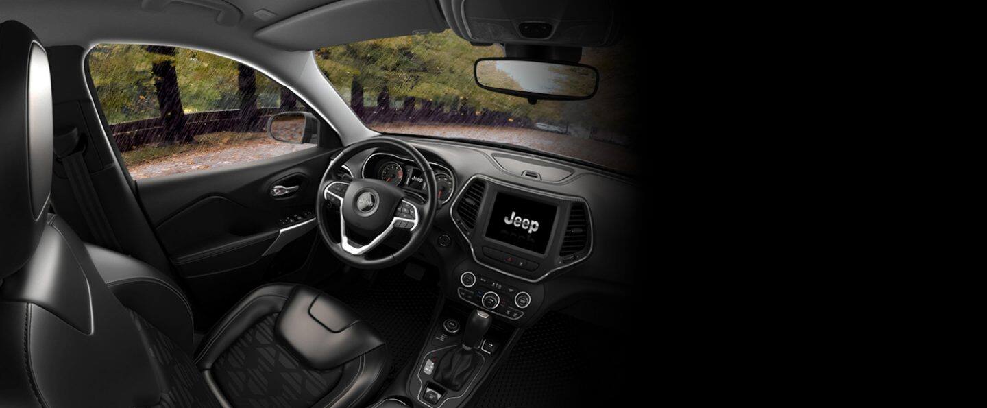 The interior of the 2022 Jeep Cherokee X with heavy rain visible outside through the windshield and driver-side window.
