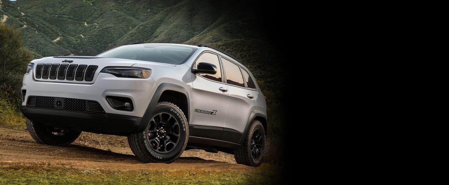 The 2022 Jeep Cherokee X being driven on a dirt road in the mountains.
