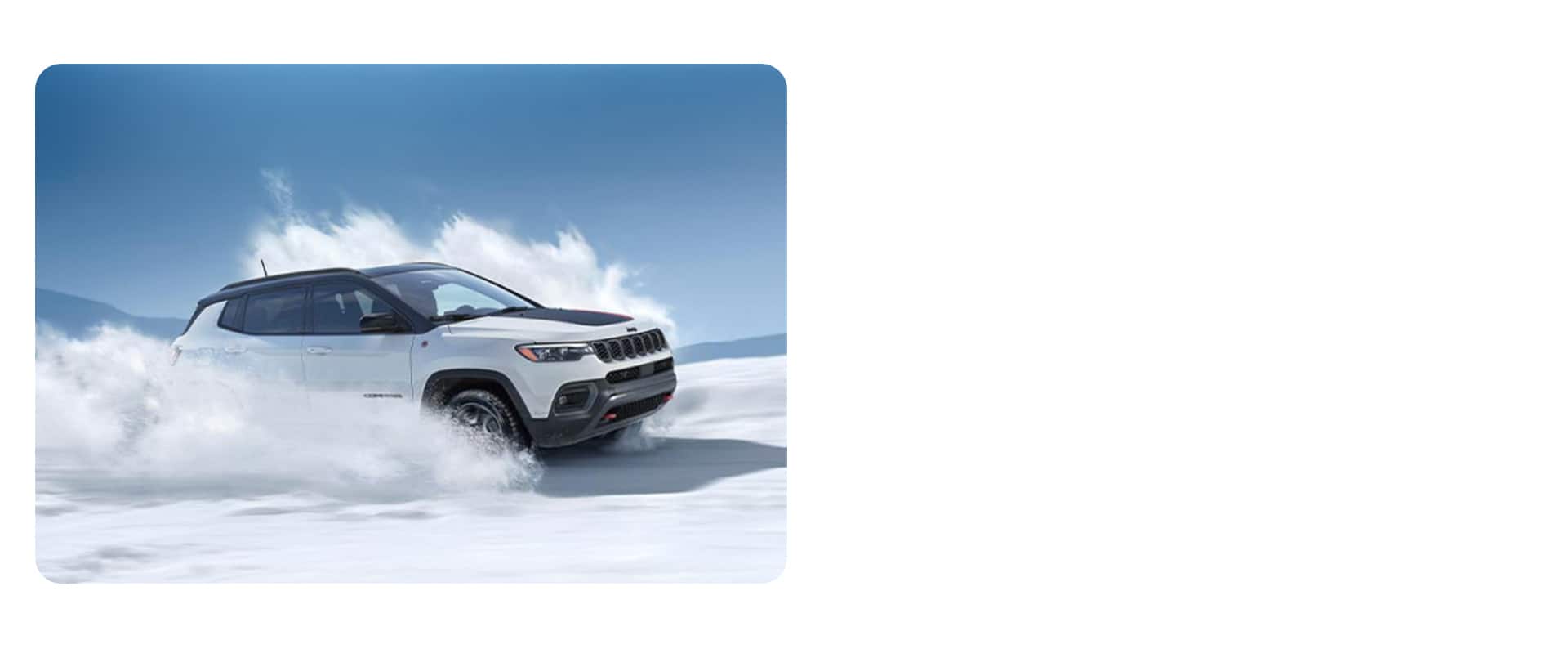 Un Jeep Compass Trailhawk 2026 blanco con un aplique negro en el capó circulando por una superficie nevada.