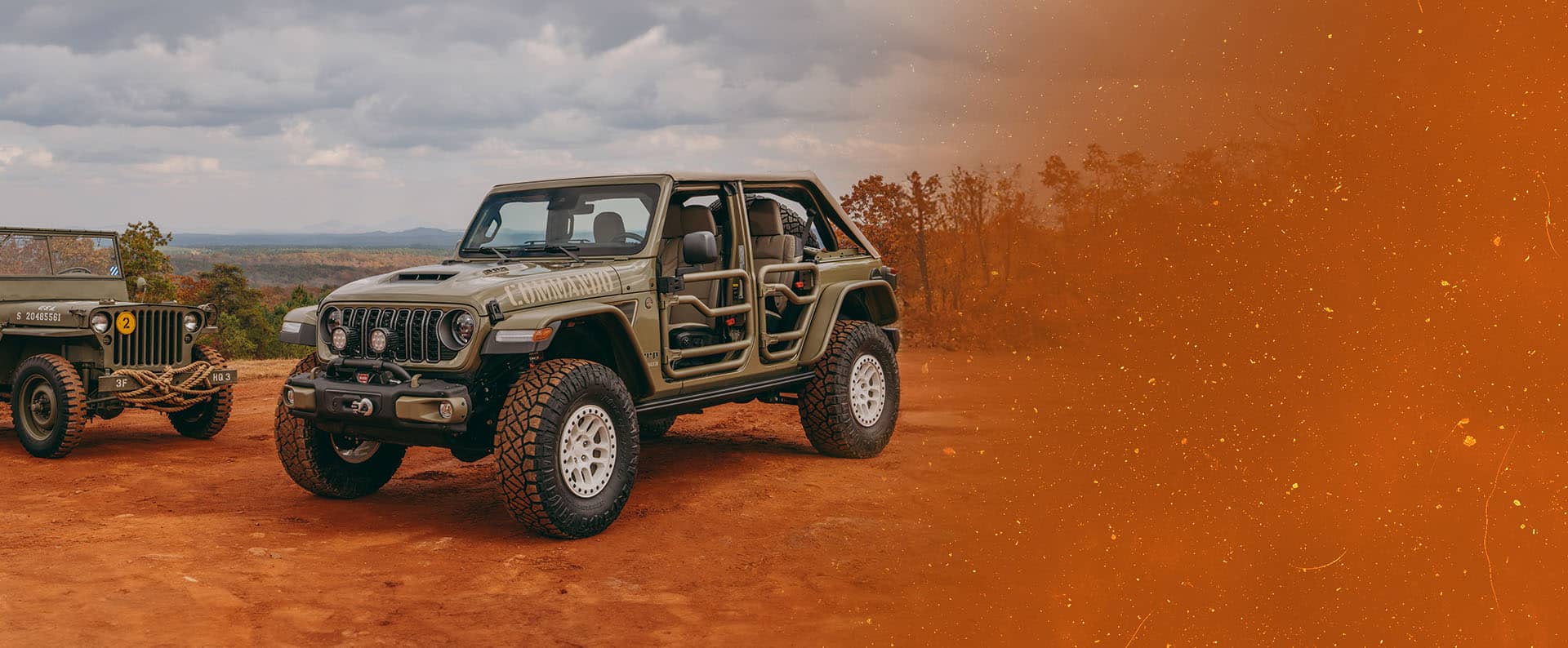 A vintage military jeep on the left and an olive drab 2026 Jeep Wrangler Commando with tube doors on the right, both parked on a clearing in the mountains. Fox Factory Vehicles.