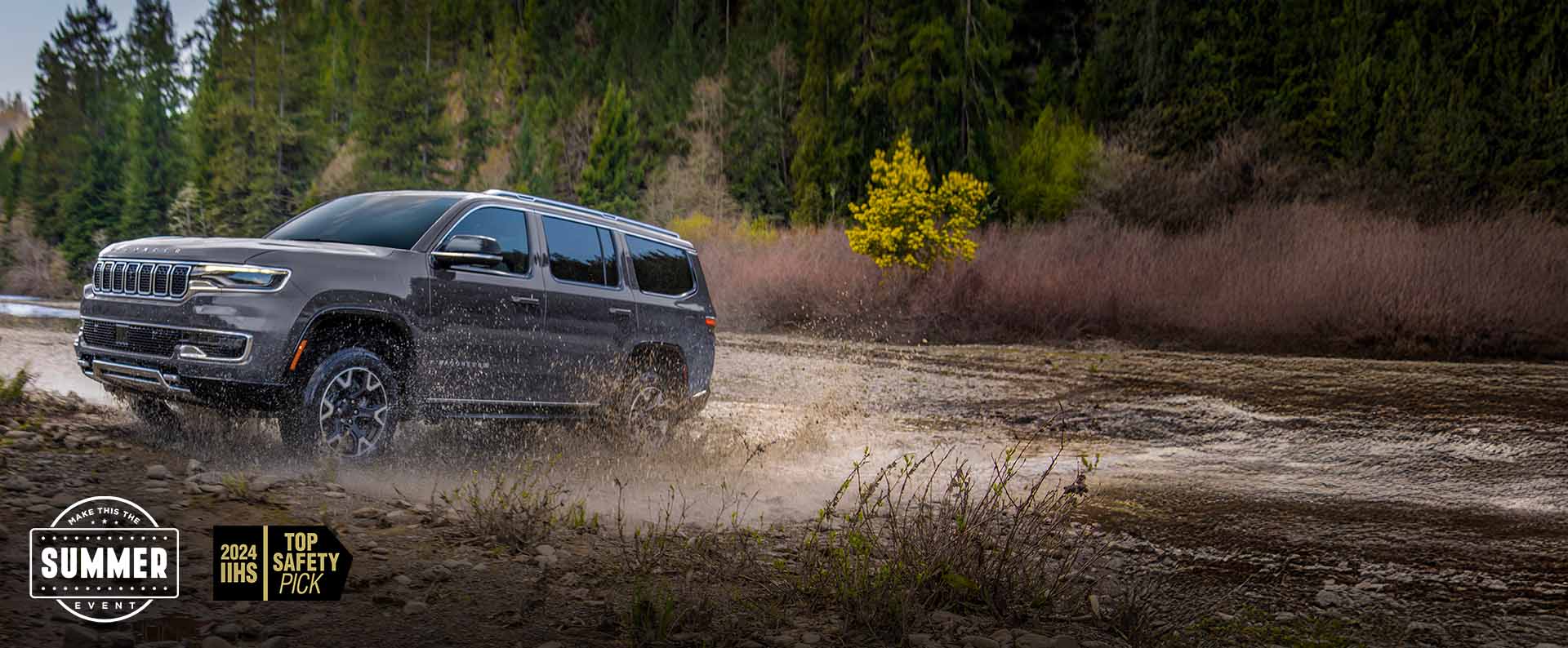 A grey 2024 Grand Wagoneer  L Series 3 exiting a muddy stream off-road. Make this the summer event.