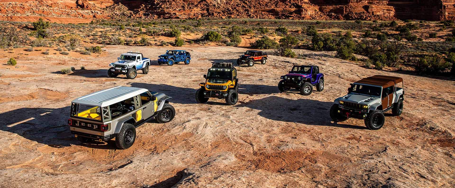 Un grupo de siete vehículos conceptuales Jeep estacionados en un claro, en el desierto.
