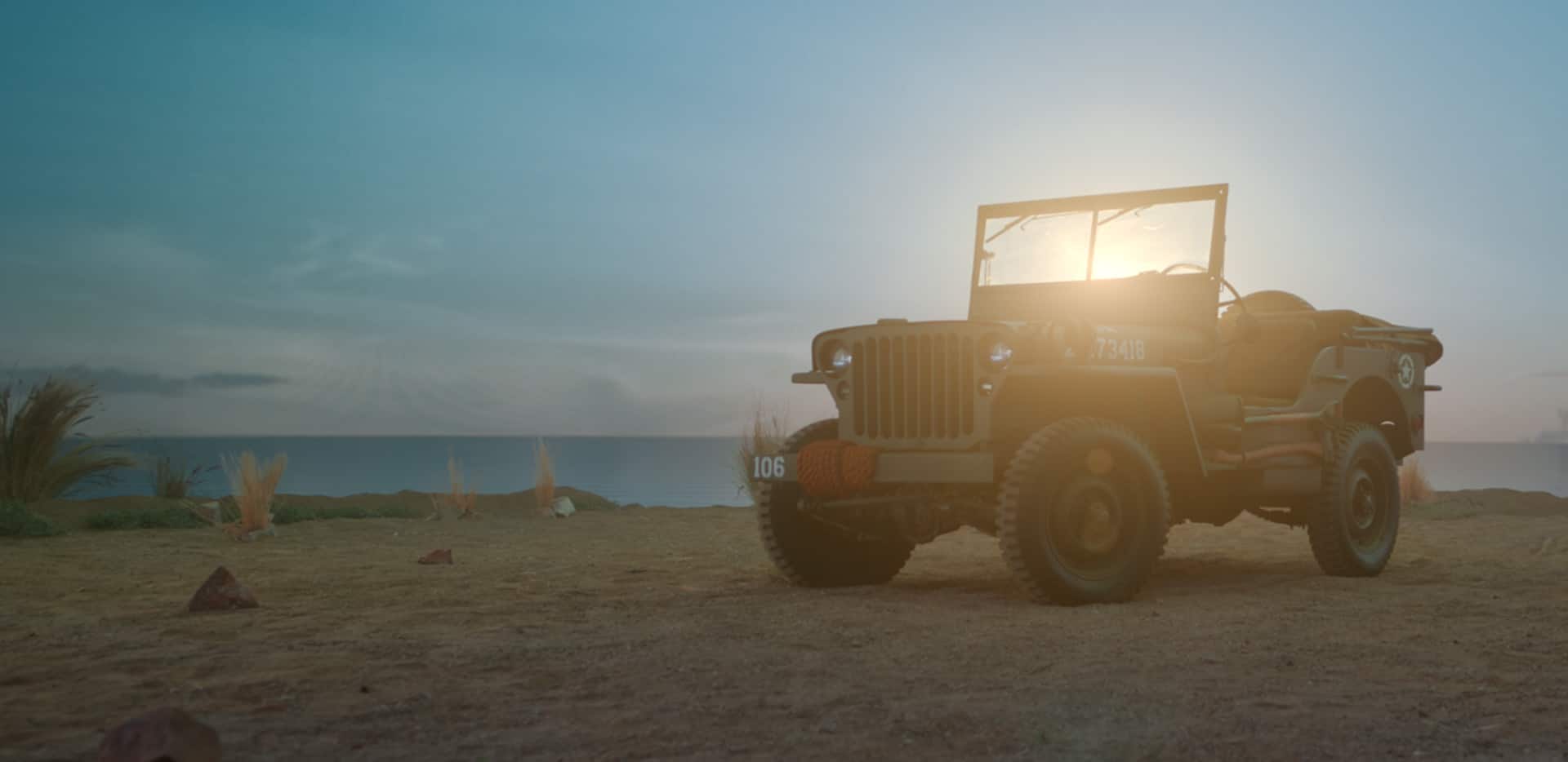 A vintage Willys MB model parked on a sandy beach.