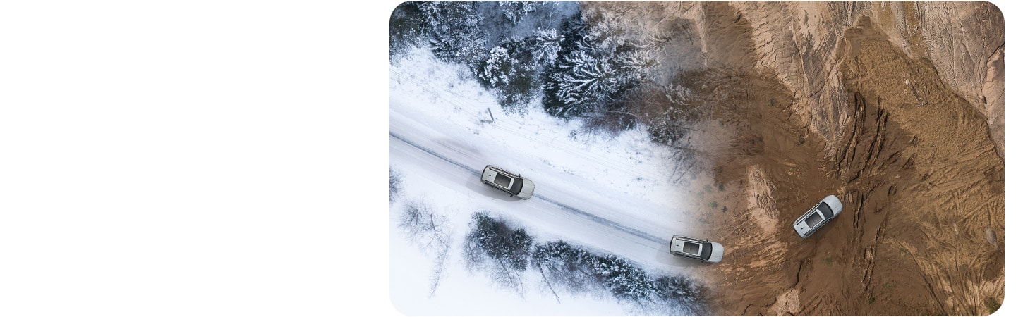 Vista aérea de tres vehículos blancos Jeep Grand Cherokee 2026 circulando por una superficie que pasa de ser un camino cubierto de nieve en el bosque a un sendero rocoso todoterreno en las montañas.
