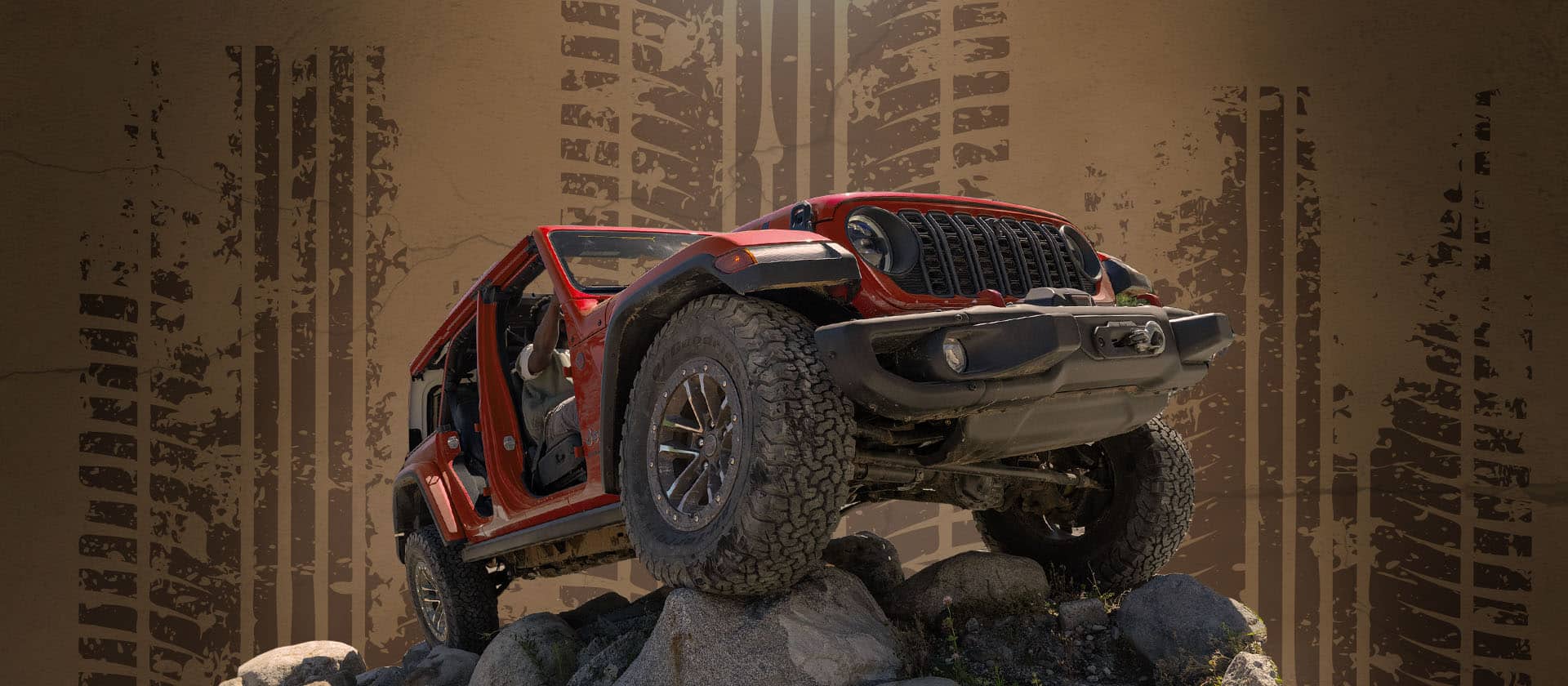 Un Jeep Wrangler Rubicon X 2026 rojo con neumáticos grandes. Con las puertas y el techo desmontados, mientras trepa por una colina de rocas. Toma desde un ángulo bajo.