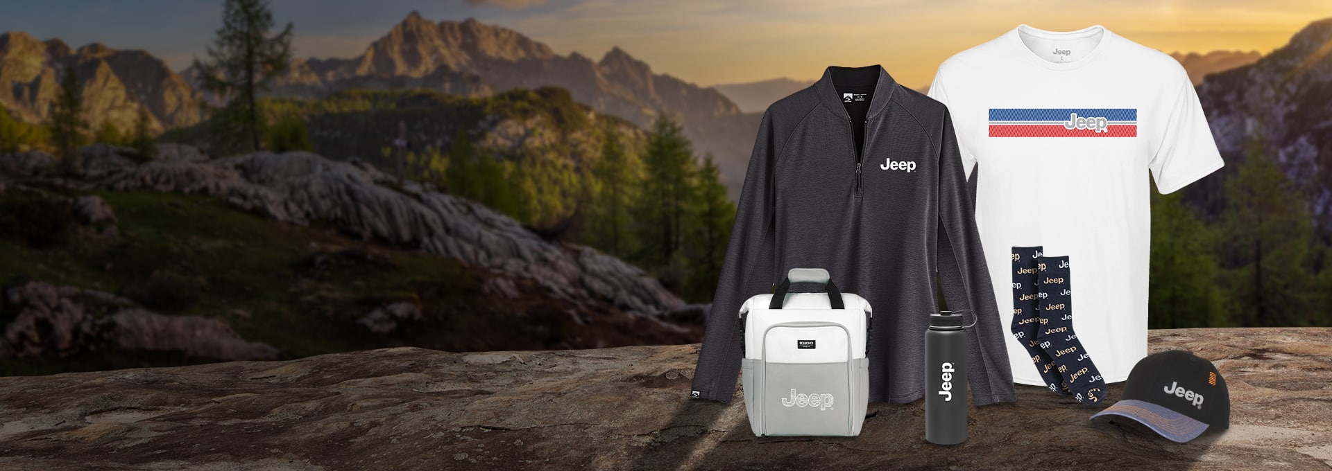 A set of Jeep Brand merchandise including a women's gray Renewer Quarter Zip Pullover, a men's white Jeep Patriotic T-Shirt, a gray and white Jeep Igloo Seadrift Backpack Cooler, a black Jeep Stainless Steel Water Bottle, black Jeep men't dress socks and a black and gray Jeep Structured Cap with Orange Stitching.