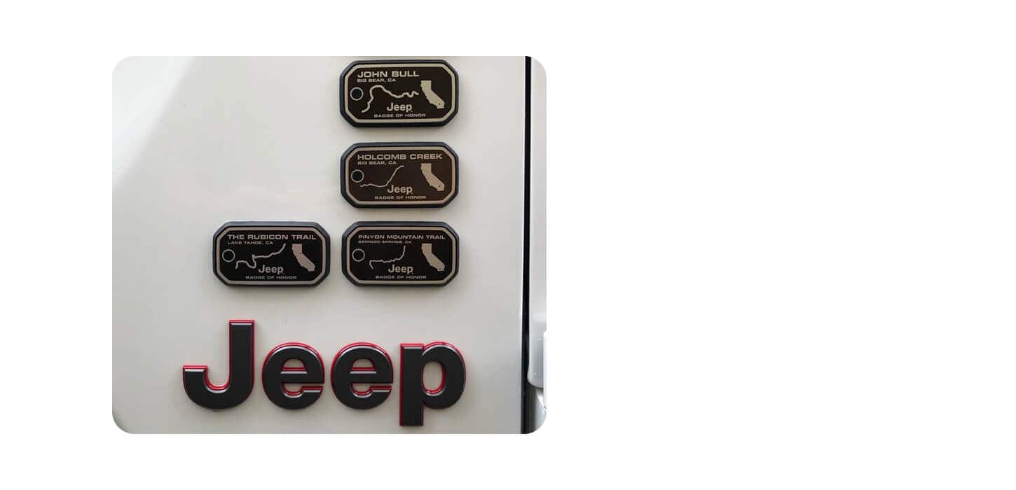 El emblema Jeep en el exterior de un vehículo de la marca Jeep, junto con cuatro Emblemas de Honor de la misma marca.
