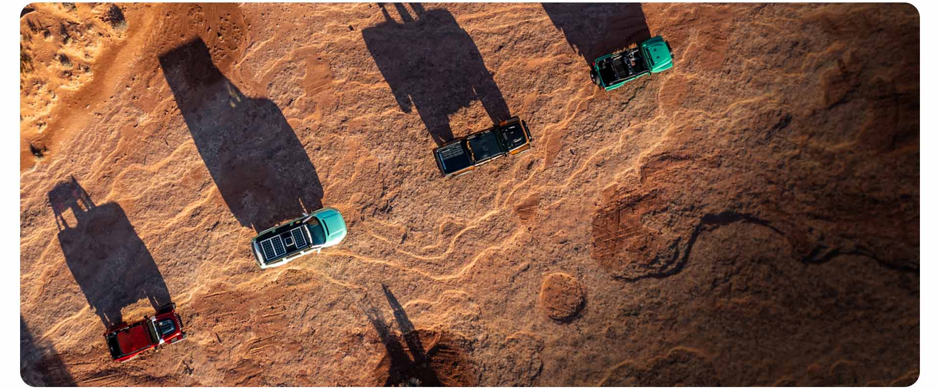 A high overhead angle of four Jeep Brand concept vehicles traveling one after another on a mountain trail in Moab, Utah.