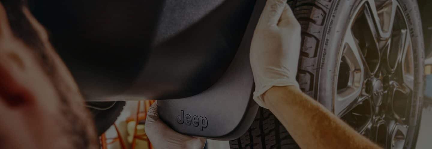 Close-up of hands working on a Jeep Brand vehicle.
