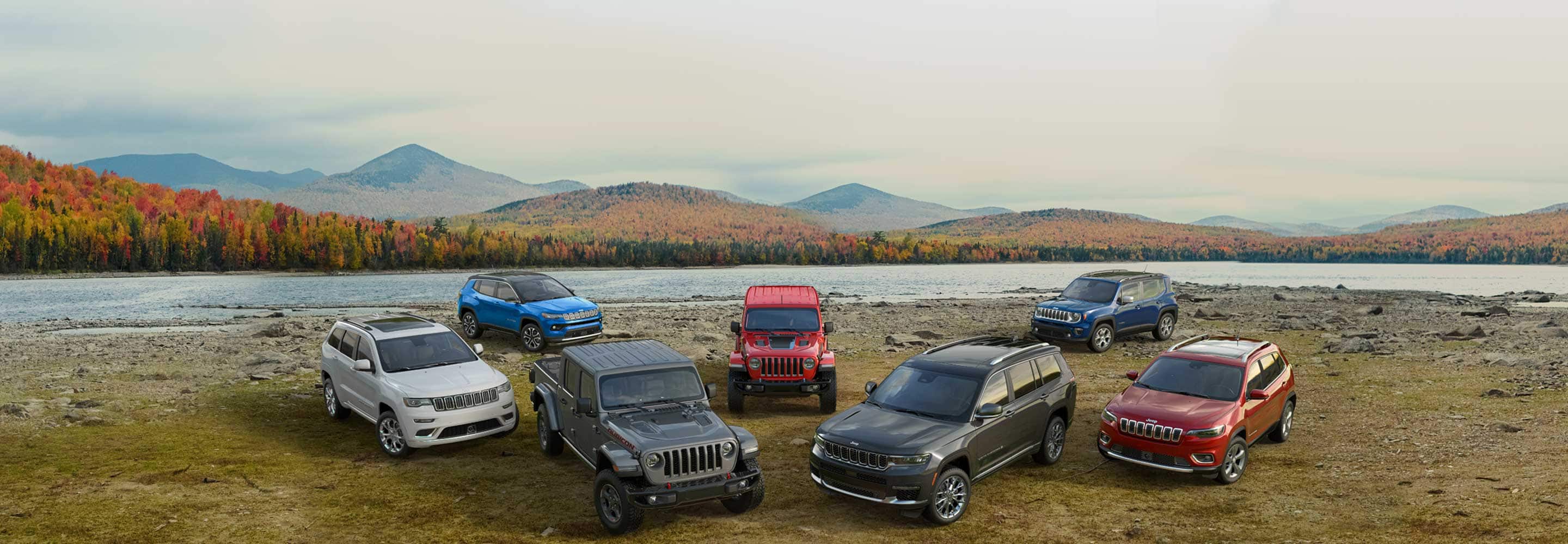 A lineup of seven 2021 and 2022 Jeep Brand vehicles on a riverbank. 