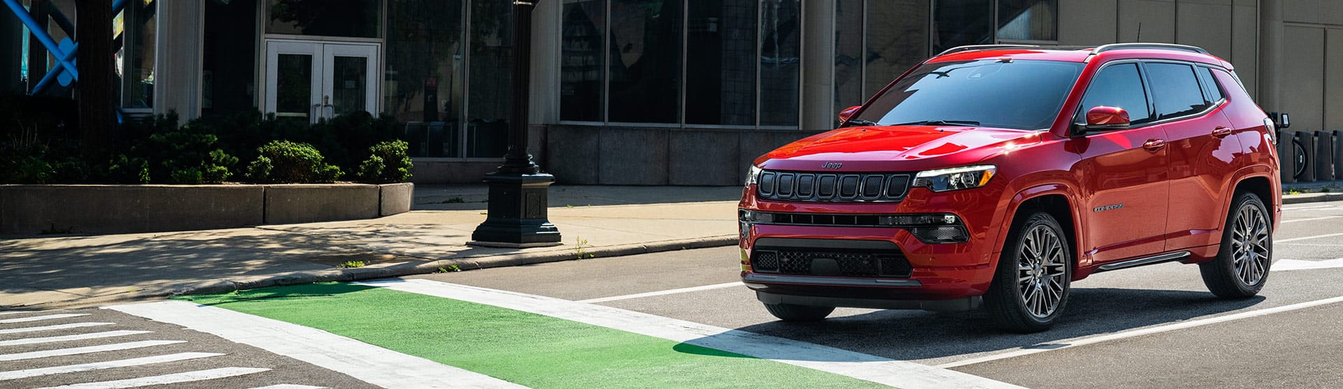 A 2022 Jeep Compass Red Edition stopped at a crosswalk intersection on a city street.