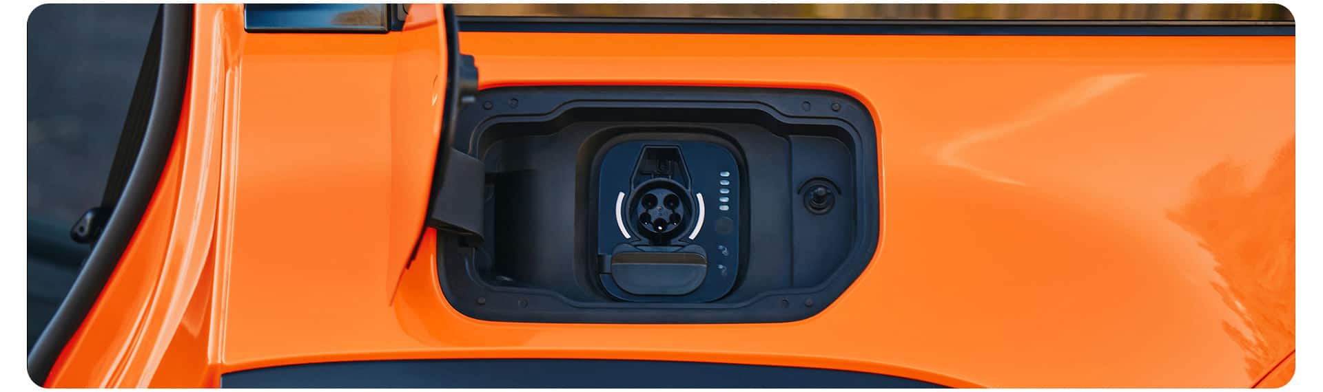 El puerto de carga de un Jeep Recon 2026 naranja.