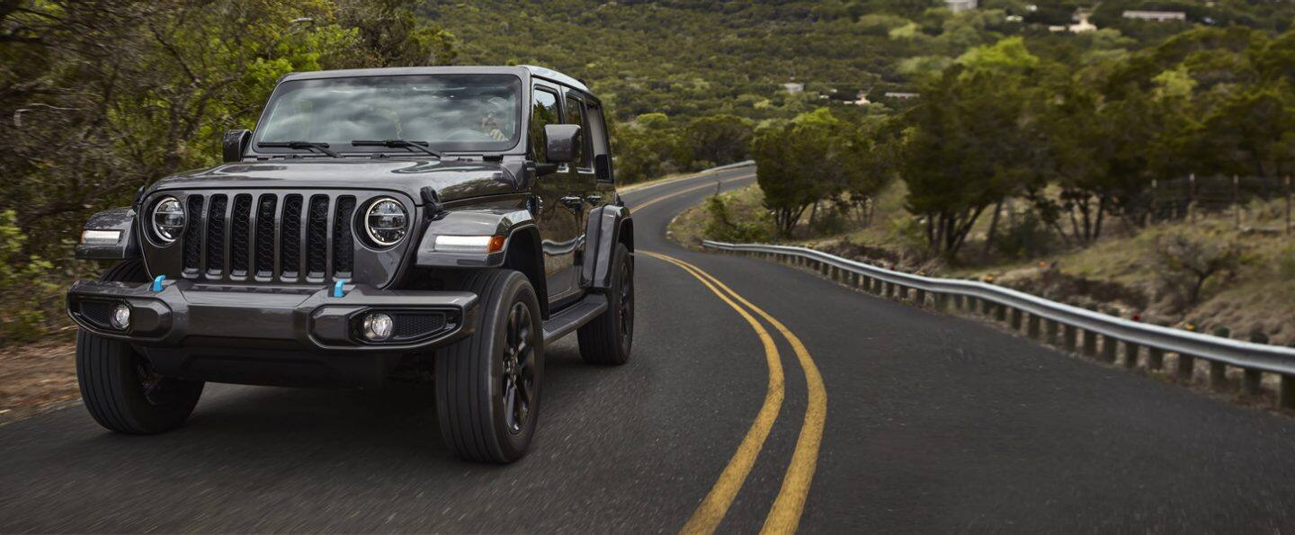 Una Jeep Gladiator Rubicon 2020 plateada estacionada en una playa sin el techo, remolcando una moto acuática personal.