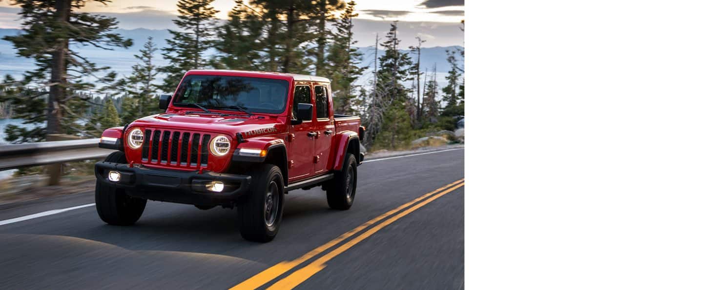 A red 2020 Jeep Gladiator Rubicon being driving on a mountain road.