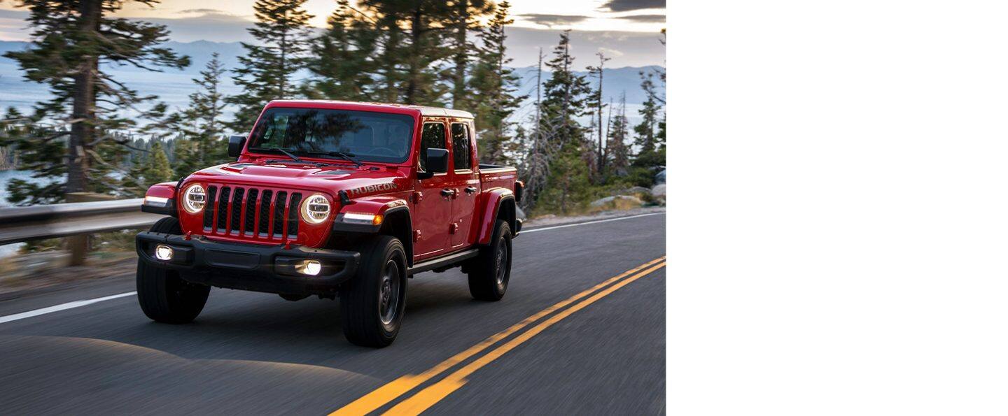 Una Jeep Gladiator Rubicon 2020 roja andando por un camino de montaña.