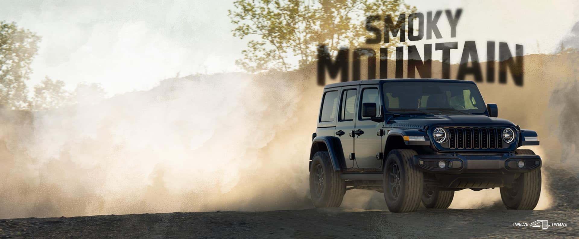 Front three-quarter passenger-side view of a black 2027 Jeep Wrangler Smoky Mountain parked on a dirt road, with a thick cloud of dust in warm, hazy light.