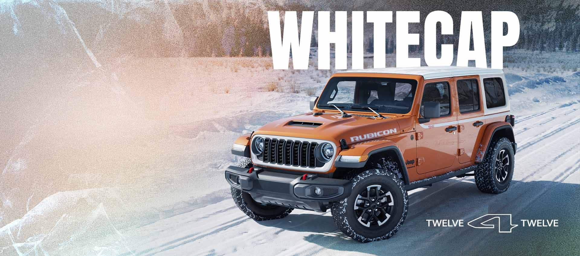 An orange 2026 Jeep Wrangler Rubicon Whitecap traveling down a snow-covered road with a forest of evergreens in the background. Whitecap. 12 for 12.