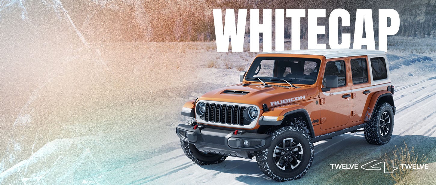 An orange 2026 Jeep Wrangler Rubicon traveling down a snow-covered road with a forest of evergreens in the background. Whitecap. 12 for 12.