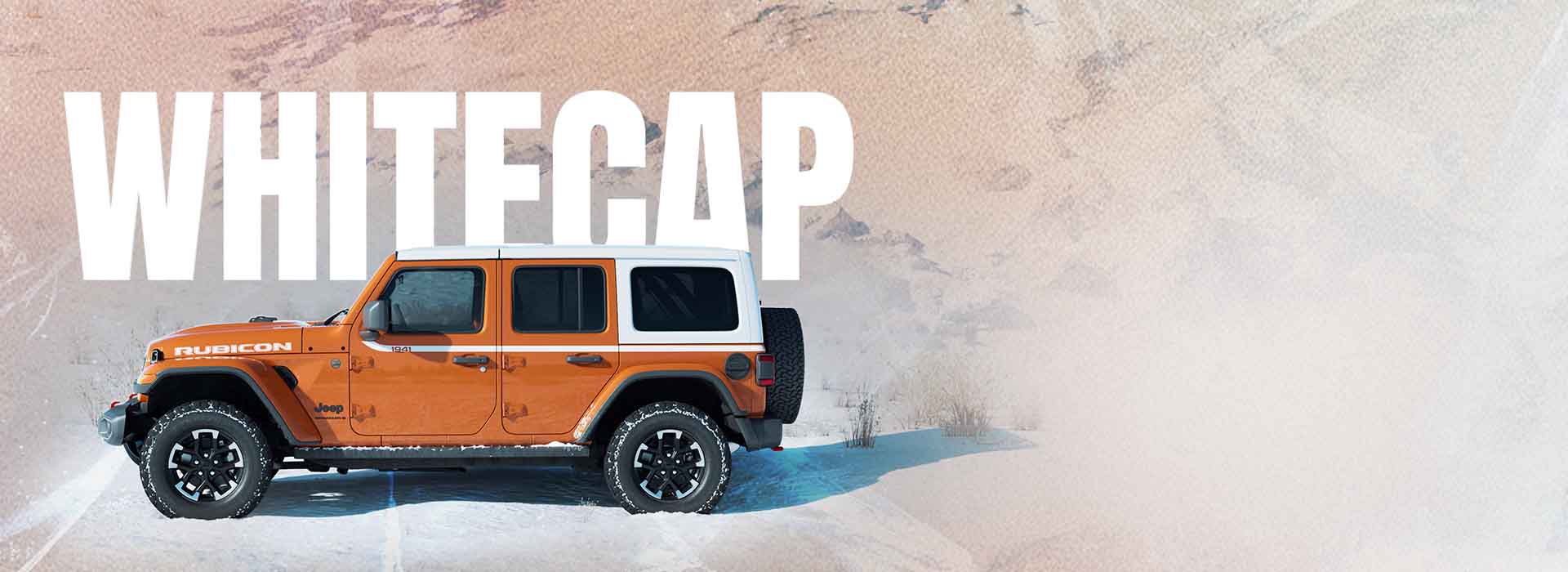 A driver-side profile of an orange 2026 Jeep Wrangler Rubicon Whitecap parked on a snow-covered clearing, with mountains in the background. Whitecap.