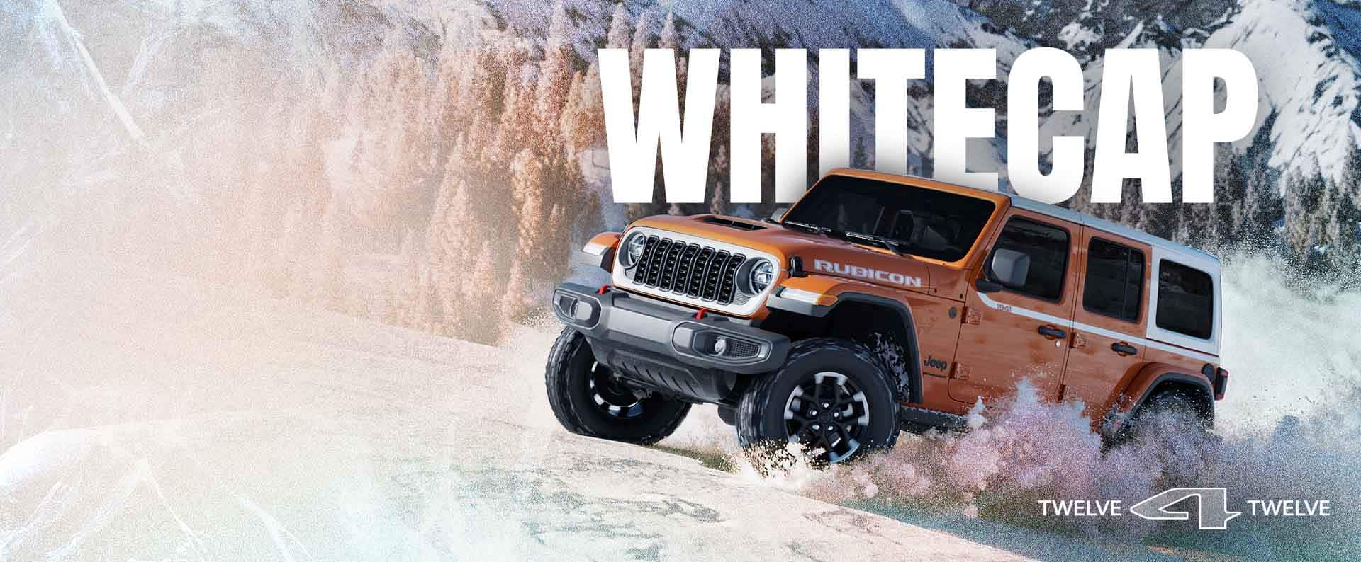 An orange 2026 Jeep Wrangler Rubicon Whitecap ascending a snow-covered trail off-road, with a forest of evergreens in the background. Whitecap. 12 for 12.