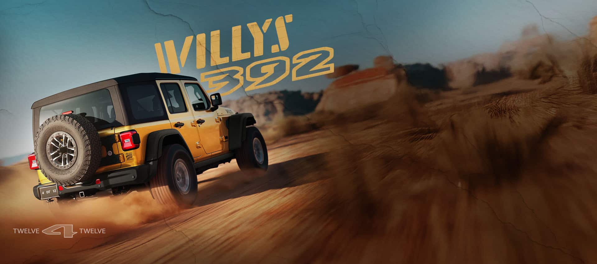 A passenger-side rear angle of a gold 2026 Jeep Wrangler Willys 392 with a black top, traveling on a sandy trail, off-road in the desert. Willys 392. 12 for 12.