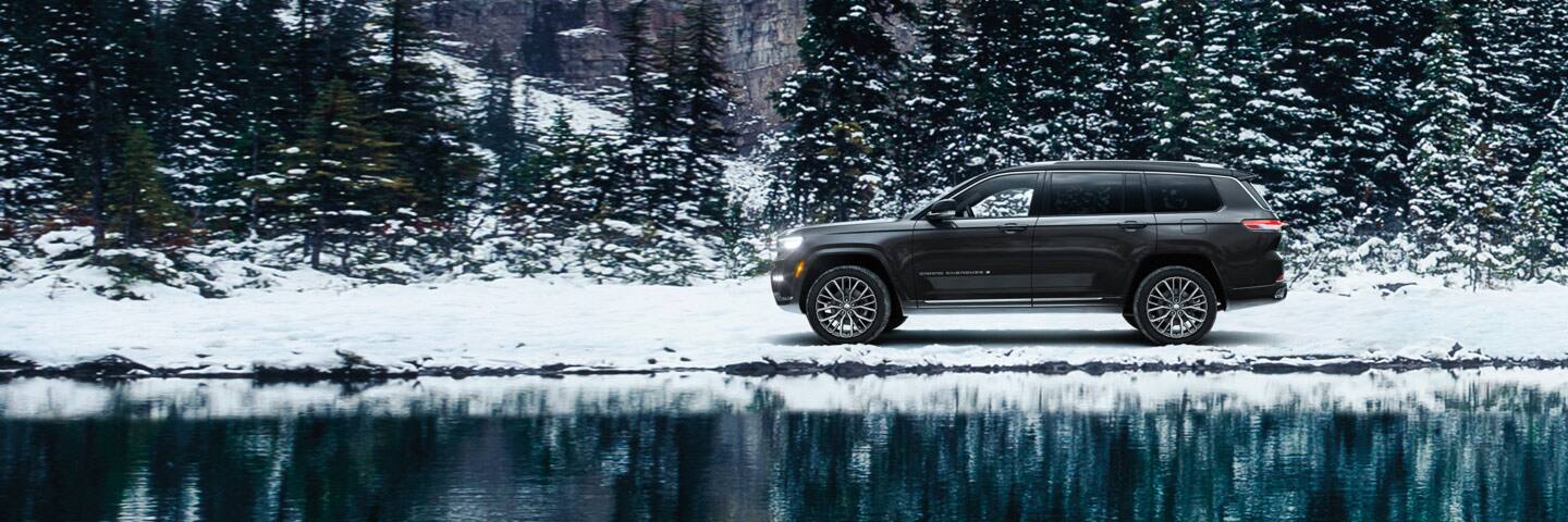 The 2022 Jeep Grand Cherokee Summit Reserve parked on snowy ground beside a lake.