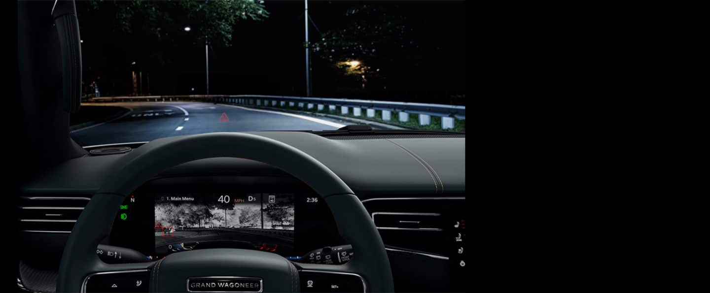 The dark highway ahead, visable through the windshield of the 2024 Grand Wagoneer, as the Driver Information Digital Cluster displays a thermal image of a deer beside the road.