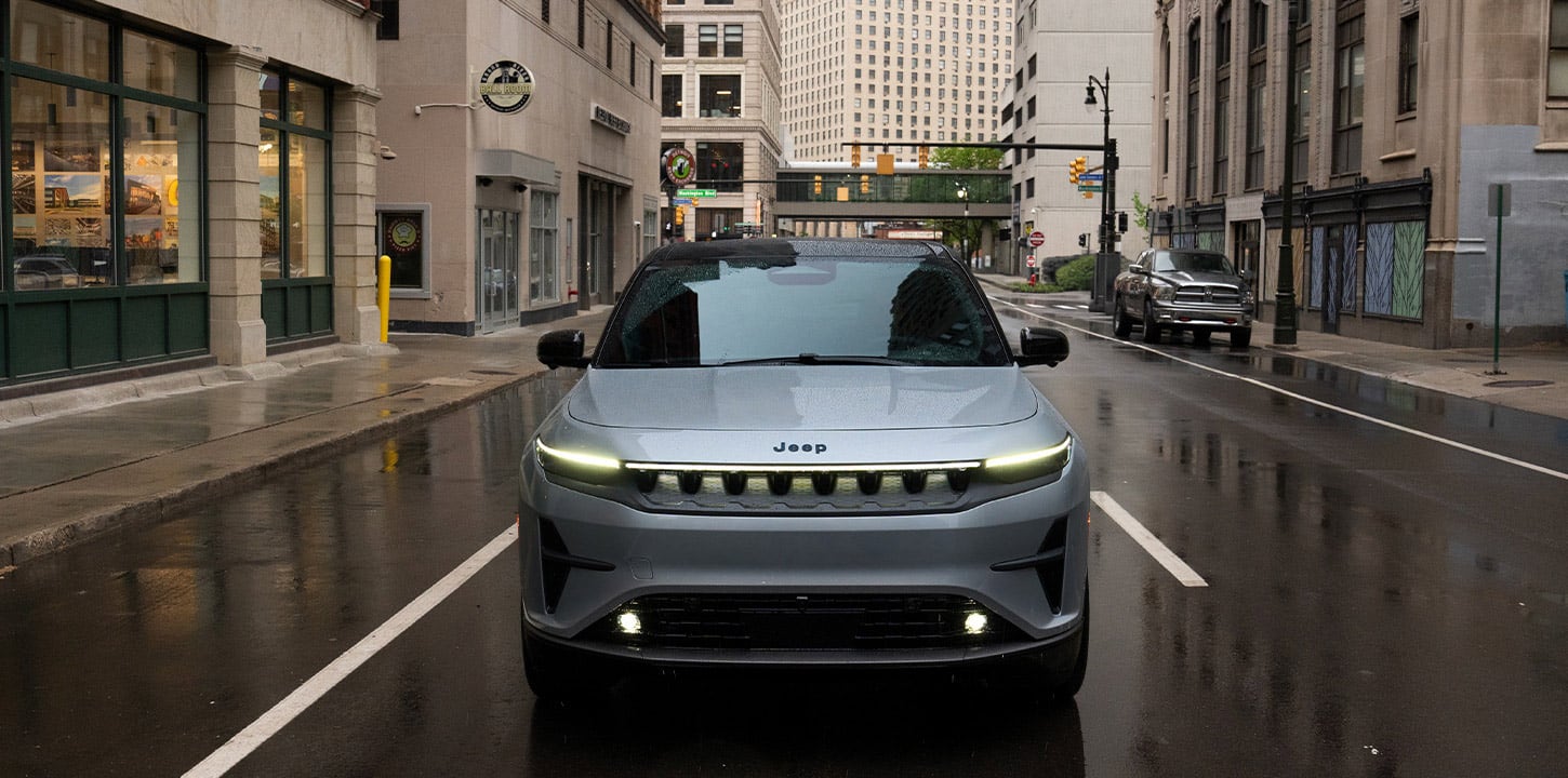 A silver 2025 Jeep Wagoneer S Launch Edition traveling down a city street in the rain.