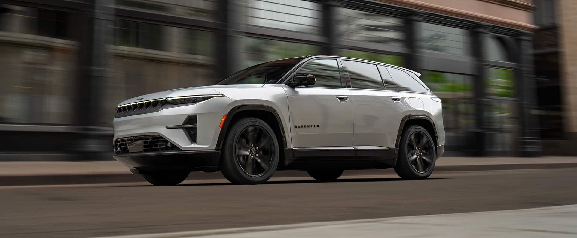 A white 2025 Jeep Wagoneer S Launch Edition traveling on a city street with the background blurred.