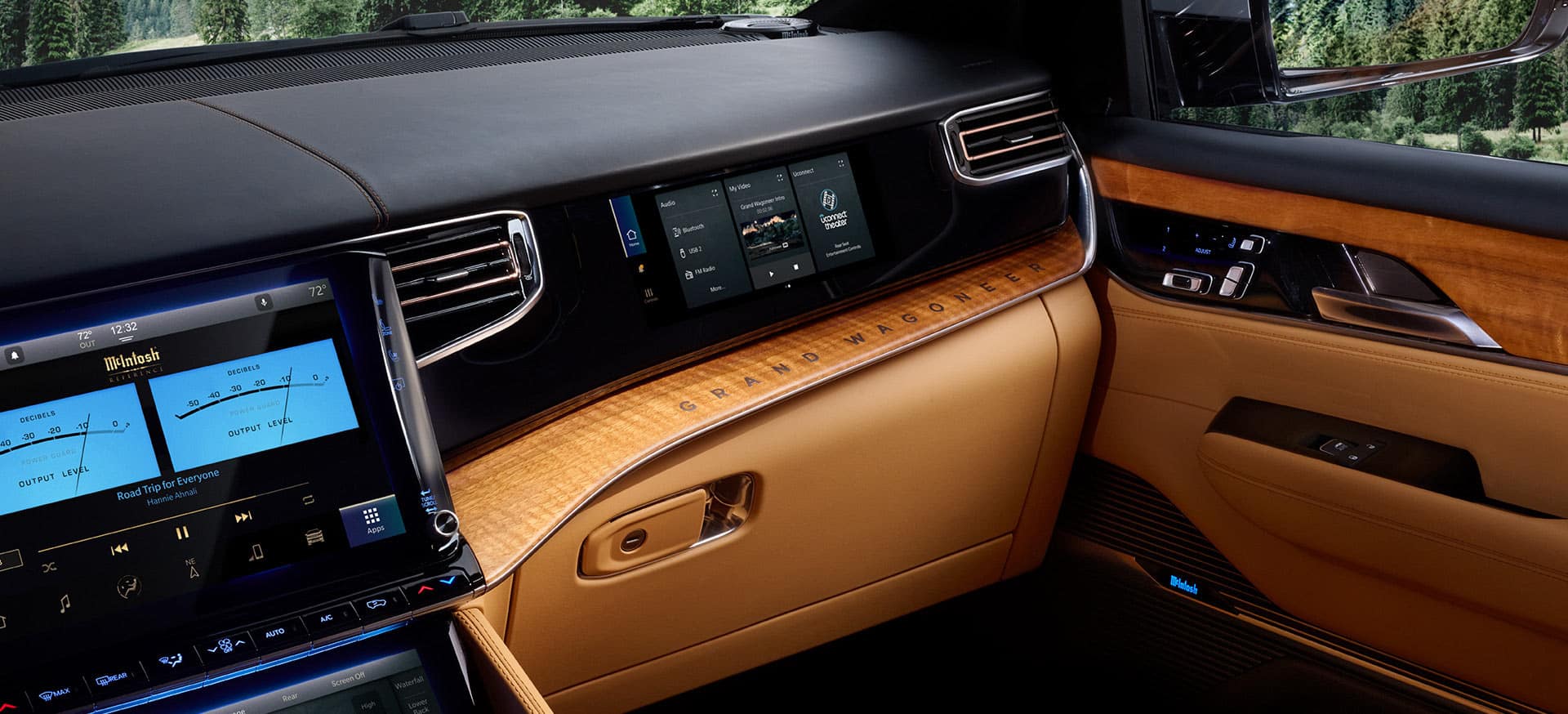 The front passenger seat area of the 2025 Jeep Grand Cherokee Series 3, with the real wood interior trim, the Front Passenger Interactive Display, the large glove compartment and the Uconnect touchscreen displaying the output levels of the McIntosh Entertainment System.