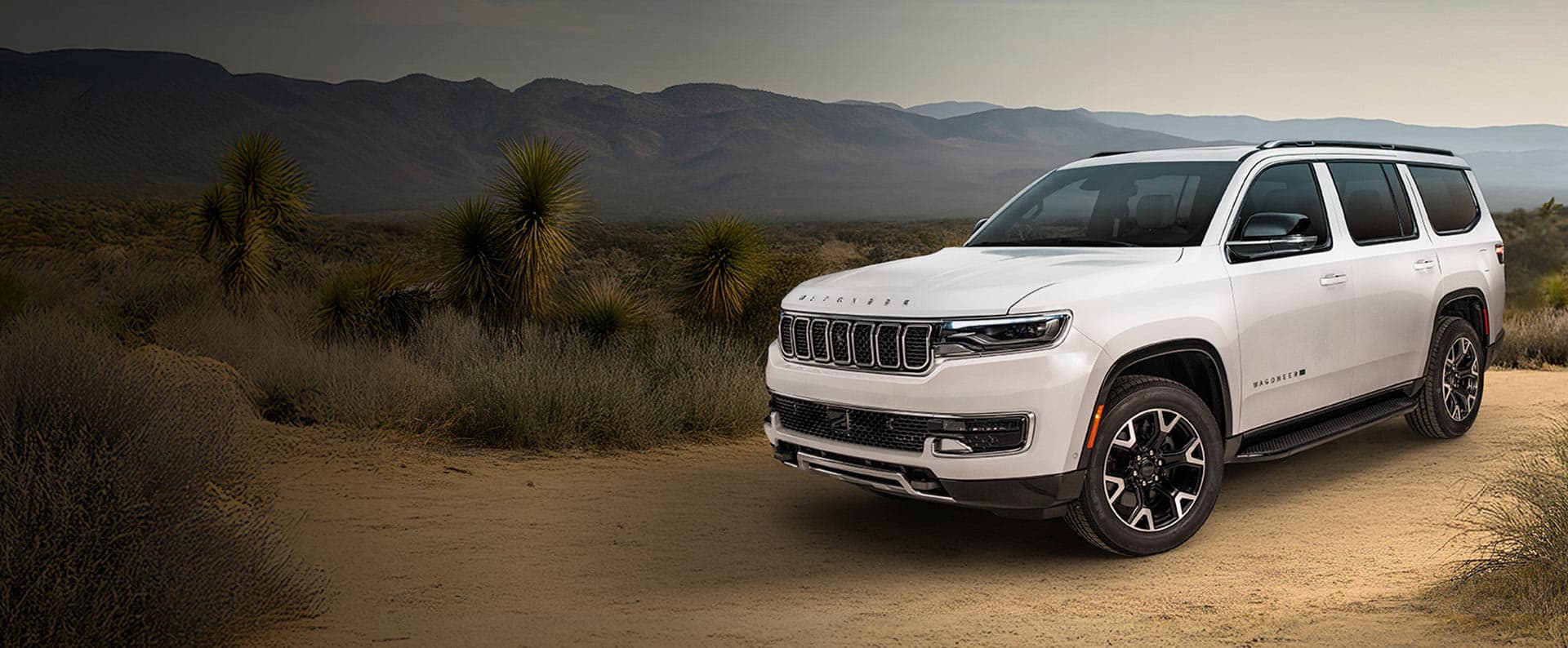 A white 2025 Jeep Wagoneer Texas Trail parked on a clearing in the desert, off-road.